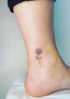 a woman's foot with a small flower tattoo on the side of her leg