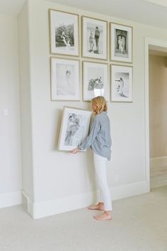 a woman standing in front of a wall with pictures hanging on it's side