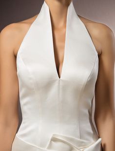 a woman wearing a white dress with a halter neckline and bow at the waist