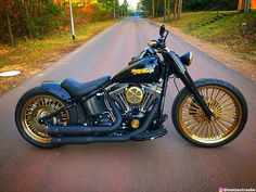 a black and gold motorcycle parked on the side of a road in front of trees