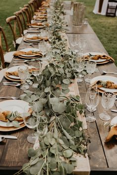 the long table is set with plates and place settings for an outdoor dinner or party