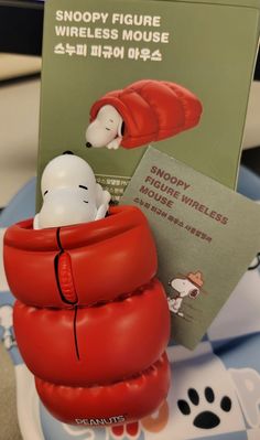 a snoopy figurine is sitting in a red cup with a book on it