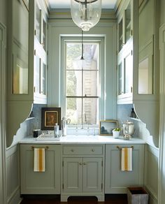 a kitchen with green cabinets and white counter tops in front of a window that is open to the outside