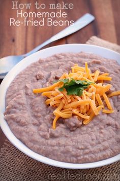 a bowl of food with cheese on top and a spoon next to it that says how to make homemade re - fried beans