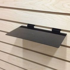 a metal shelf mounted to the side of a wooden wall