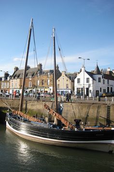 a boat is docked in the water next to some buildings and a bridge with people on it