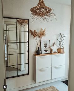 a room with a dresser, mirror and plants on it