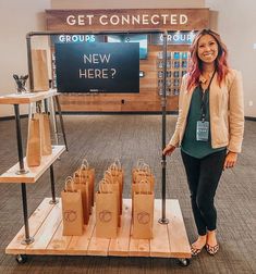 a woman standing in front of a table with bags on it and a sign that says get connected