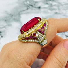 Red Ruby Stone Women Ring Add a touch of royalty to your collection with this exquisite ruby ring. Featuring a large, radiant red ruby as the centerpiece, this ring captures attention with its bold, vibrant color. The main stone is surrounded by an array of smaller rubies  meticulously set to enhance its sparkle and brilliance. Crafted in a vintage style, this ring combines timeless elegance with a striking, modern flair. The sides are adorned with beautifully detailed accents, complementing the Luxury Lab-created Ruby Ring, Exquisite Red Cubic Zirconia Rings, Luxury Ruby Gemstone Ring, Luxury Red Ruby Ring For Anniversary, Luxury Ruby Halo Ring, Luxury Ruby Rings As Gifts, Luxury Ruby Ring As Gift, Luxury Red Ruby Gemstone Ring, Luxury Red Ruby Ring With Accent Stones