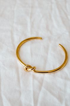 Our Knot Bangle is timeless and elegant. It can be worn by itself or as a layering piece with your watch. PRODUCT DETAILS 18k Gold plated stainless steel polished Nickel free SIZING & MEASUREMENT5.8cm inner diameter, 3.2mm thickness CARE For the longest shine avoid contact with water, perfume, moisturizer and hairspray. We recommend you remove your jewelry when showering, exercising, at the beach, or swimming in chlorinated water. All pieces featuring pearls and natural gemstones are very precio Classic Gold Stainless Steel Cuff Bracelet, Adjustable Stainless Steel Bangle With Polished Finish, Adjustable Gold-plated Bangle With Polished Finish, Adjustable Gold Stainless Steel Cuff Bracelet, Adjustable Gold Timeless Bangle, Gold Adjustable Timeless Bangle, Timeless Adjustable Gold Cuff Bracelet, Timeless Adjustable Gold Bangle, Adjustable Yellow Gold Stainless Steel Bangle