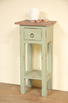 a small wooden table with a cup on top