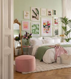 a bedroom decorated in pastel green and white with pictures on the wall above the bed