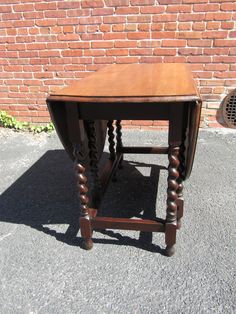 an old wooden table sitting in front of a brick wall with no one around it