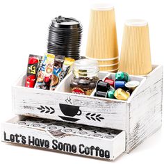 a wooden box filled with coffee cups and candy bar items on top of a white table