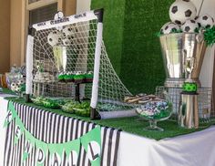 a table topped with soccer balls and cupcakes next to a goalie net