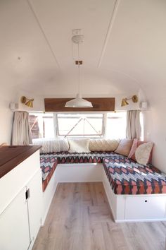 the interior of an rv with a couch, window seat and storage area in it