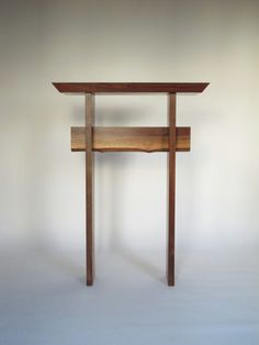 a small wooden table sitting on top of a white floor in front of a wall