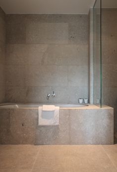 a bathroom with a bathtub, towel rack and glass shower door in the corner