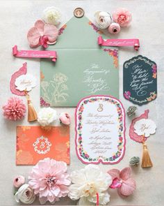 the wedding stationery is laid out with flowers and ribbons on it's side