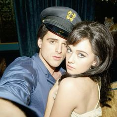 a young man and woman are posing for a photo in front of a blue curtain