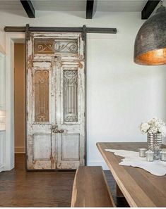 an old door is opened to reveal a dining room with white walls and wood floors