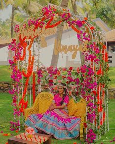 a woman sitting on top of a yellow couch under a canopy covered in pink flowers