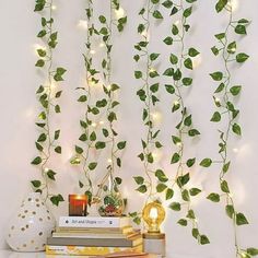 some books are sitting on a table with green leaves hanging from the wall behind them