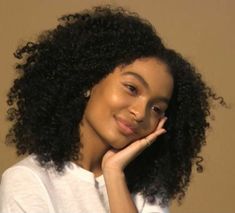 a close up of a person with curly hair and wearing a white t - shirt