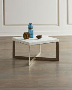 a white table with two blue vases on it in front of an empty wall