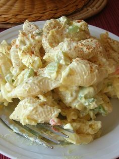 a white plate topped with pasta salad next to a fork