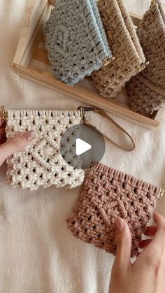 a person holding a crocheted purse next to several other items on a table