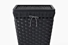 a black basket with a white string tied to the top and bottom, in front of a white background