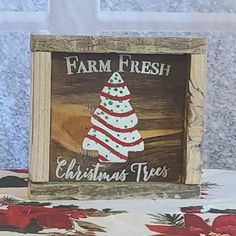 a wooden sign that says farm fresh christmas trees with a red and white striped tree on it