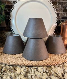 three gray lampshades sitting on top of a table next to a plate and silverware