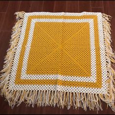 a yellow and white crocheted rug on the floor with fringes around it