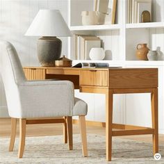 a desk with a chair, lamp and bookshelf in the background on a carpeted floor