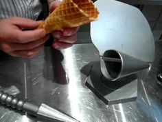 a person holding an ice cream cone in their hand while standing next to a machine