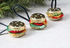 three miniature hamburgers are sitting next to a christmas tree ornament on a table