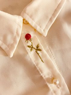 a white shirt with a rose embroidered on it