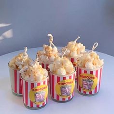 four buckets filled with popcorn sitting on top of a white table next to each other