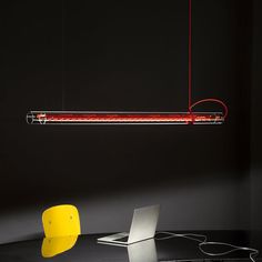 a laptop computer sitting on top of a desk under a red light hanging from the ceiling