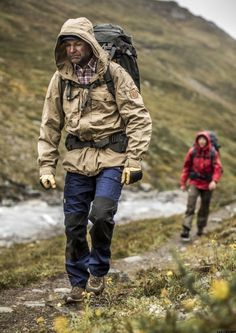 two men walking up a hill with backpacks on