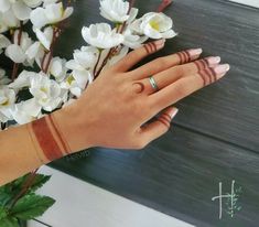 a woman's hand with two rings on it next to white flowers and greenery