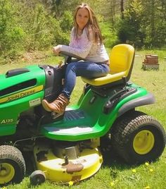 a woman sitting on top of a green lawn mower