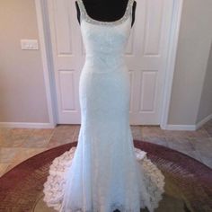 a white wedding dress is on display in front of a door with a black mannequin