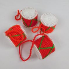 four crocheted red and white items on a table top with string attached to them