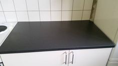 a black counter top in a kitchen next to a white stove and sink with no faucet