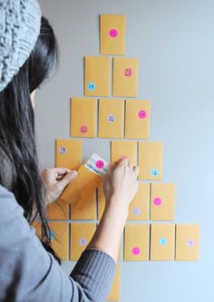 a woman is making a wall decoration with sticky notes