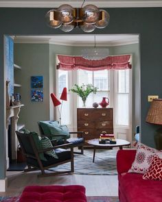 a living room filled with furniture and a fire place under a chandelier over a window