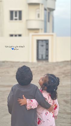 a boy and girl hugging each other in front of a building with the words love written on it